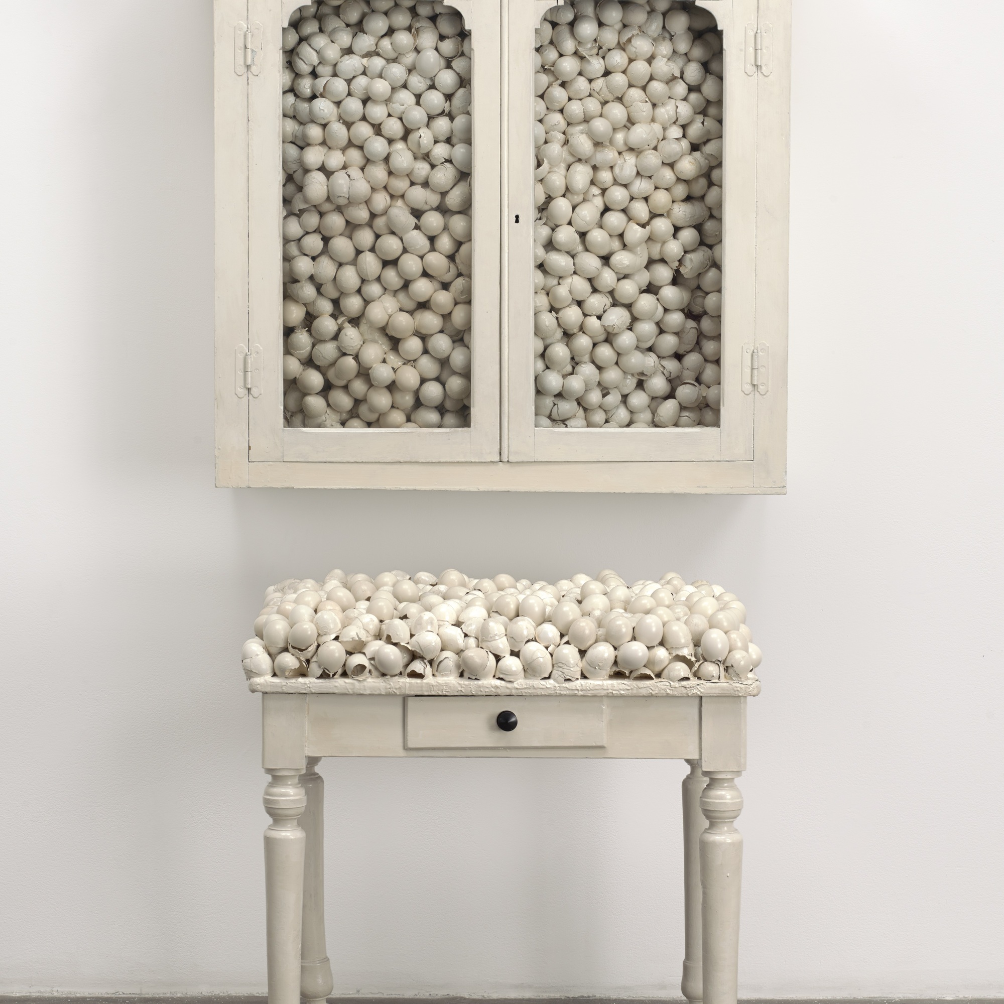 Marcel Broodthaers. Armoire blanche et table blanche (White Cabinet and White Table). 1965. Painted cabinet, table, and eggshells; cabinet 33 7/8 × 32 1/4 × 24 1/2″ (86 × 82 × 62 cm), table 41 × 39 3/8 × 15 3/4″ (104 × 100 × 40 cm). The Museum of Modern Art, New York. Fractional and promised gift of Jo Carole and Ronald S. Lauder. © 2015 Estate of Marcel Broodthaers/Artists Rights Society (ARS), New York/SABAM, Brussels