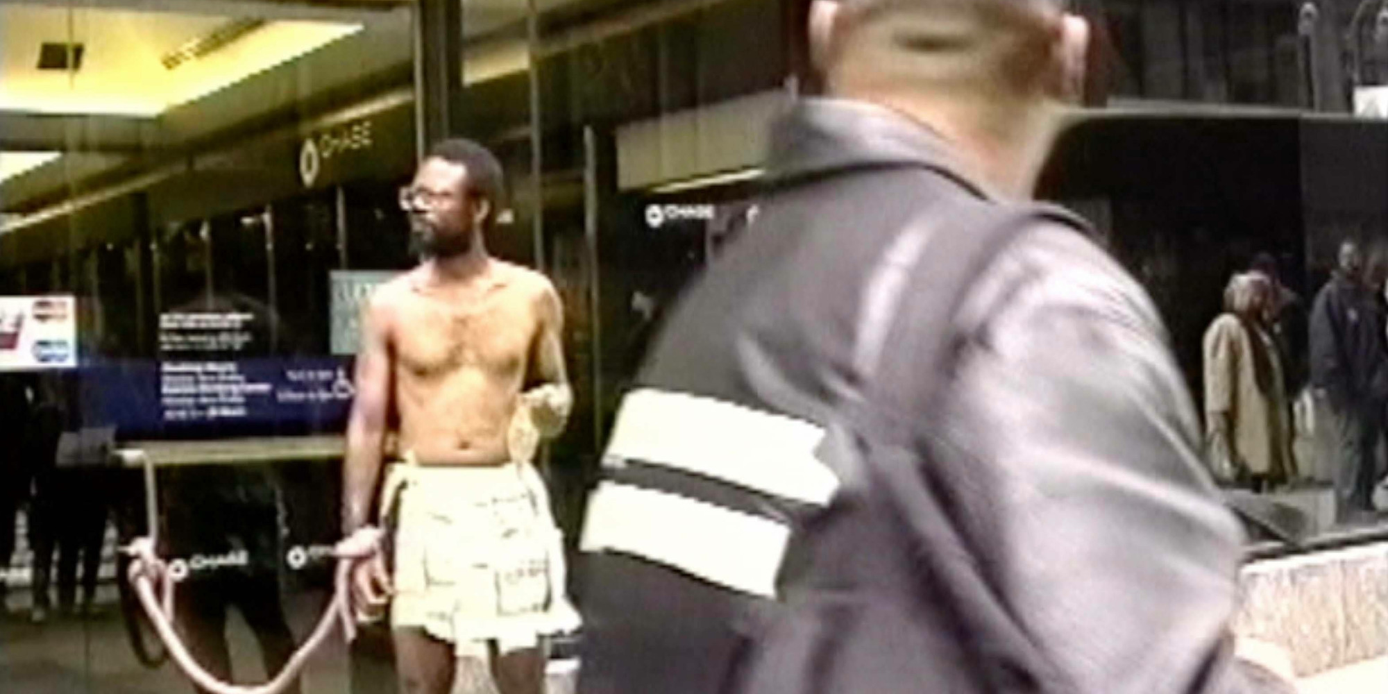 Pope.L. Still from ATM Piece. 1997. Video (color, sound), 1:54 min.; five inkjet prints; and Timberland leather boots. The Museum of Modern Art, New York. Acquired in part through the generosity of Jill and Peter Kraus, Anne and Joel S. Ehrenkranz, The Contemporary Arts Council of The Museum of Modern Art, The Jill and Peter Kraus Media and Performance Acquisition Fund, and Jill and Peter Kraus in honor of Michael Lynne. © 2021 Pope.L. Image courtesy of the artist