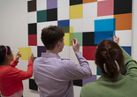 Photo: Martin Seck. © 2023 The Museum of Modern Art, New York Image description: Three people hold up sheer, colorful plastic squares to look at an artwork on the wall with a grid of black, white, and colorful painted squares by the artist Ellsworth Kelly.