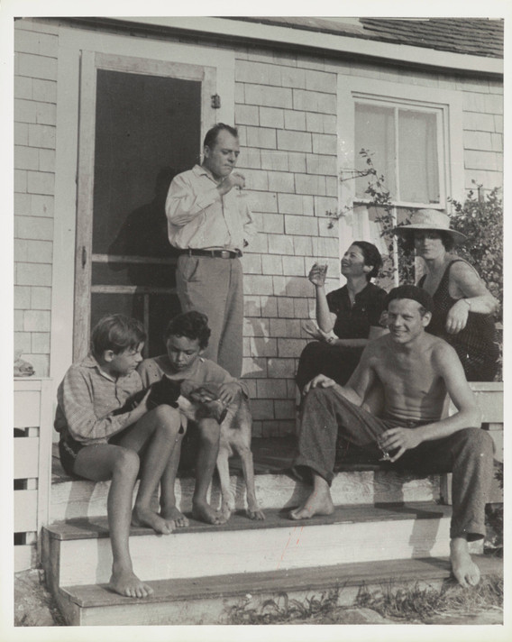 Photograph of Jackson Pollock (seated at right) on the steps of painter Thomas Hart Benton’s summer home with Rita Benton (sitting, in white hat) and author Coburn Gilman (standing), 1937