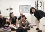 An instructor and families look at artworks together. Photo: Martin Seck