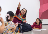 Photo: Bea MeseguerImage description: An educator and a child look upward at artwork together.
