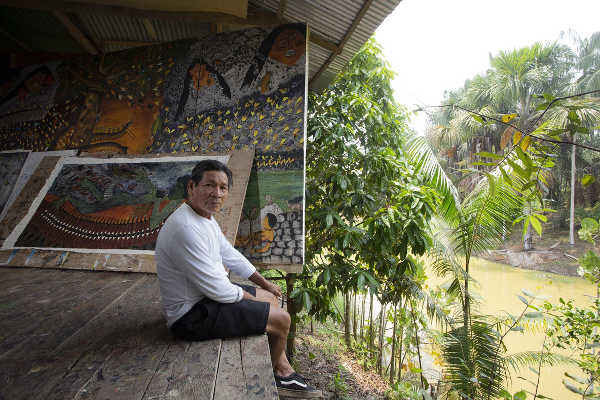 Santiago Yahuarcani fotografiado con algunas de sus pinturas en Pebas, 2024