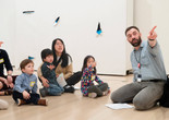 Photo: Martin SeckImage description: An educator points at an artwork while families with young children observe.