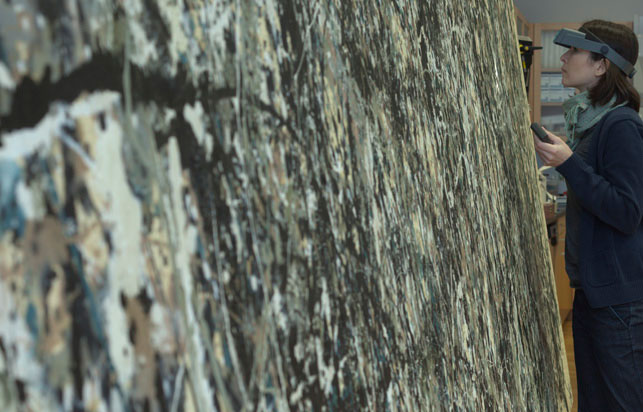MoMA Assistant Conservator Jennifer Hickey inspects the paint surface of One: Number 31, 1950 under magnification