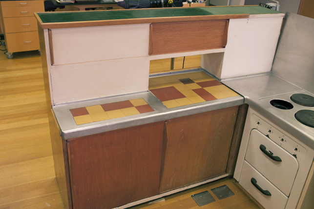 The interior side of the bar cuisine with the embedded tile countertop and cast aluminum counter. The sheet aluminum countertop around the stove can be seen on the right. The interior side of the bar cuisine with the embedded tile countertop and cast aluminum counter. The sheet aluminum countertop around the stove can be seen on the right.