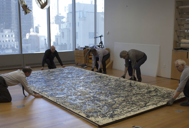 Preparators and conservators gently lower the painting