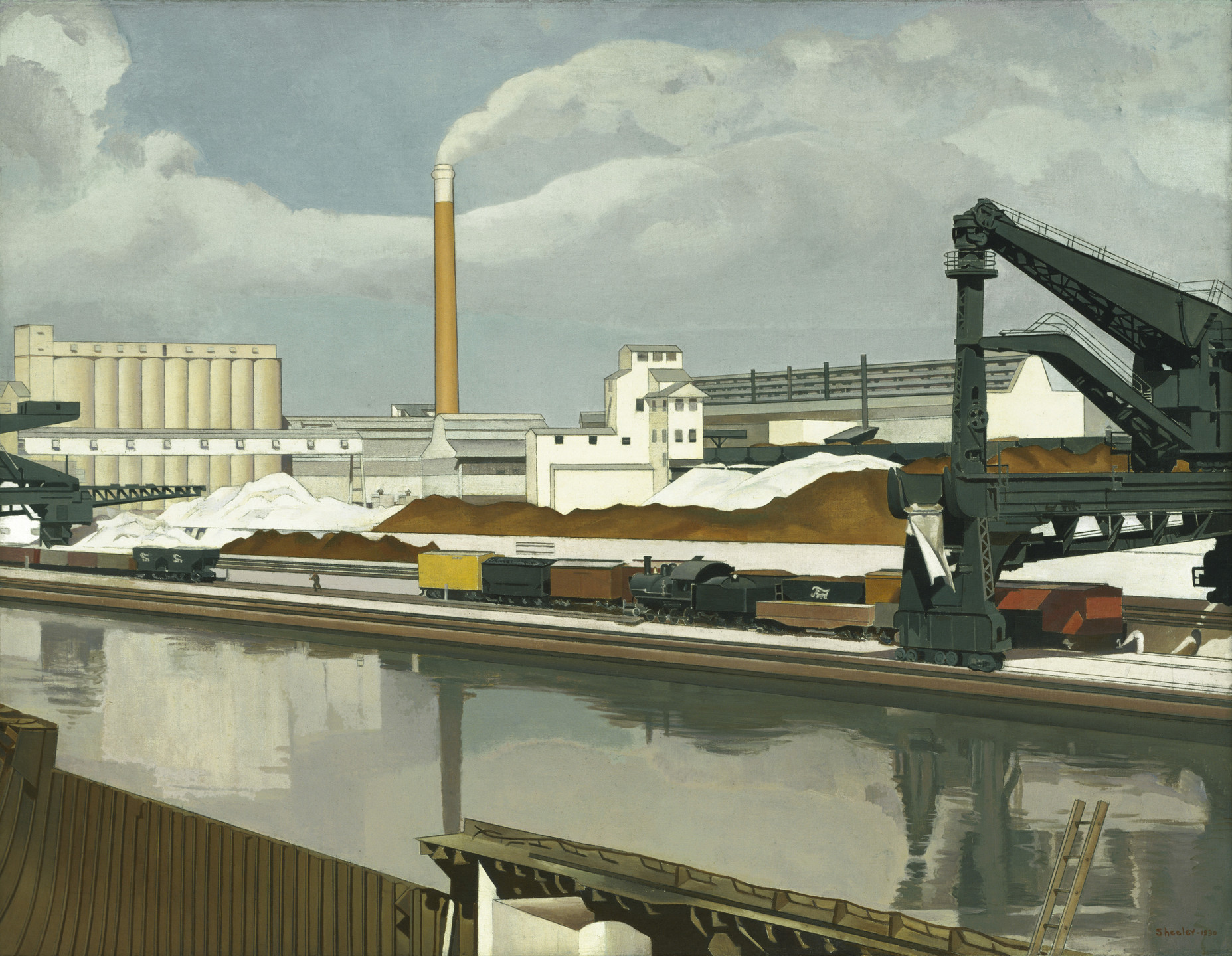 An industrial scene shows factories, large metal structures, and train cars in front of a body of water. The image predominantly features gray, white, and brown tones with a cloudy sky. This is an AI generated description. To give feedback, email ai@moma.org.