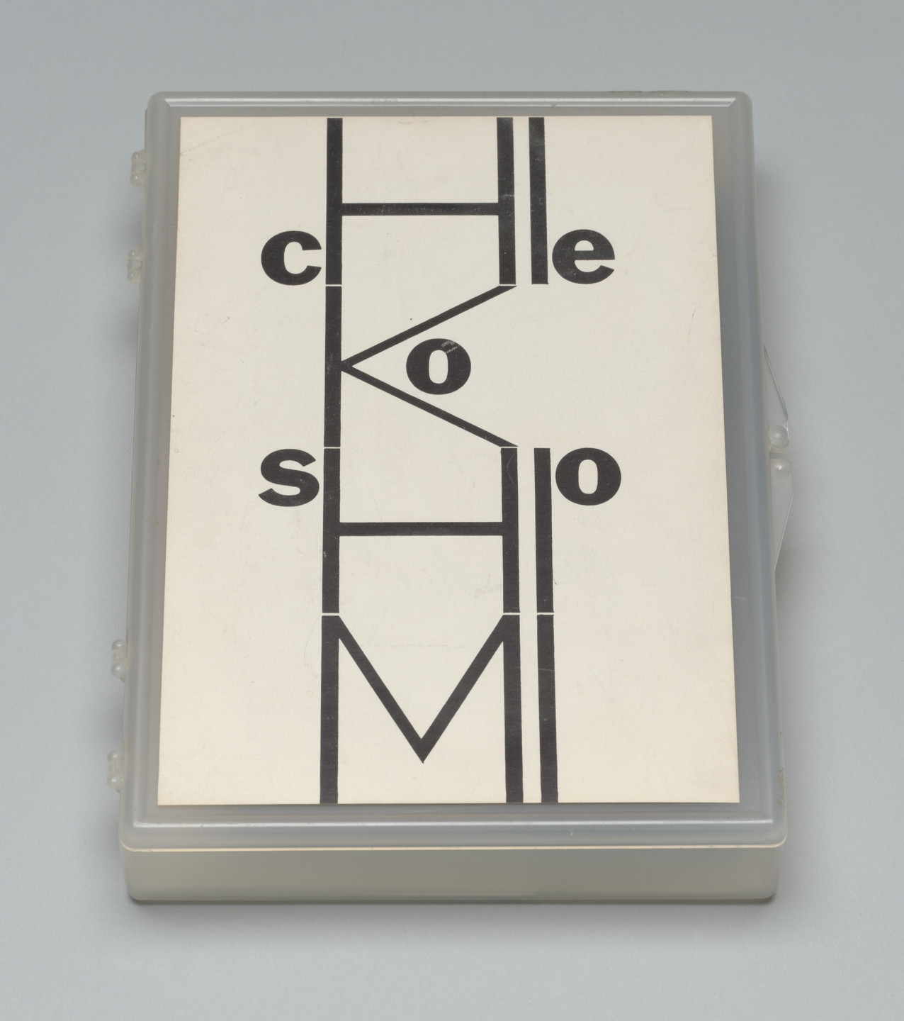 The image shows black letters &#34;cko,&#34; &#34;lle,&#34; &#34;sho,&#34; and &#34;M&#34; arranged vertically and horizontally on a white background. It is framed in a gray plastic case. This is an AI generated description. To give feedback, email ai@moma.org.