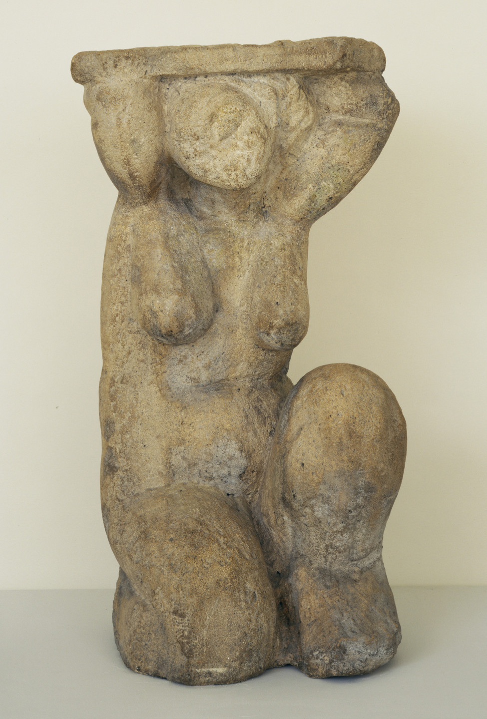 A stone-like sculpture featuring a figure kneeling with one leg up, with both arms raised over its head, supporting a horizontal slab. The sculpture is predominantly beige with grayish undertones. This is an AI generated description. To give feedback, email ai@moma.org.