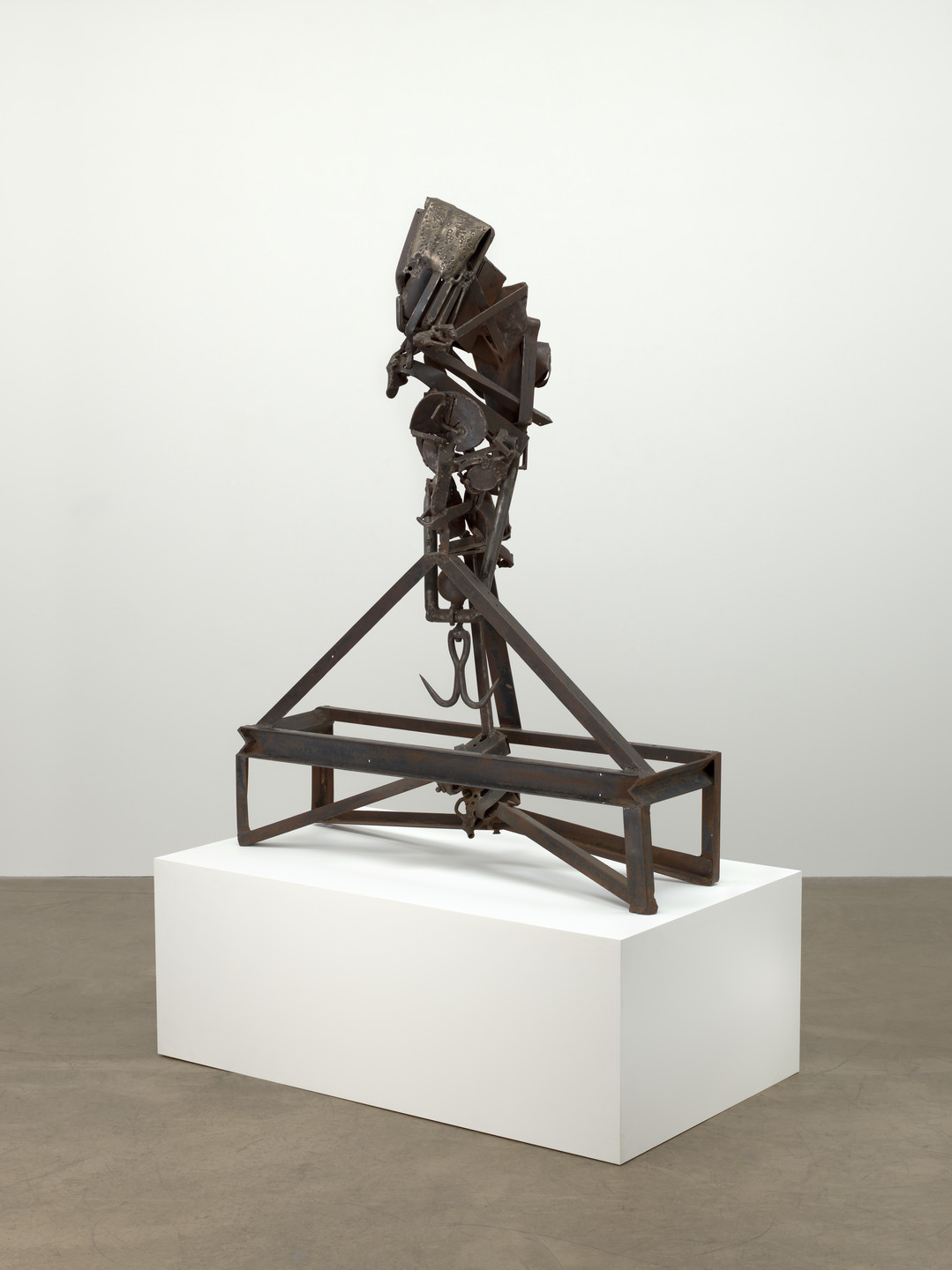A rusted metal sculpture with various geometric shapes and structures, mounted on a white rectangular pedestal. The predominant colors are dark brown and gray. This is an AI generated description. To give feedback, email ai@moma.org.