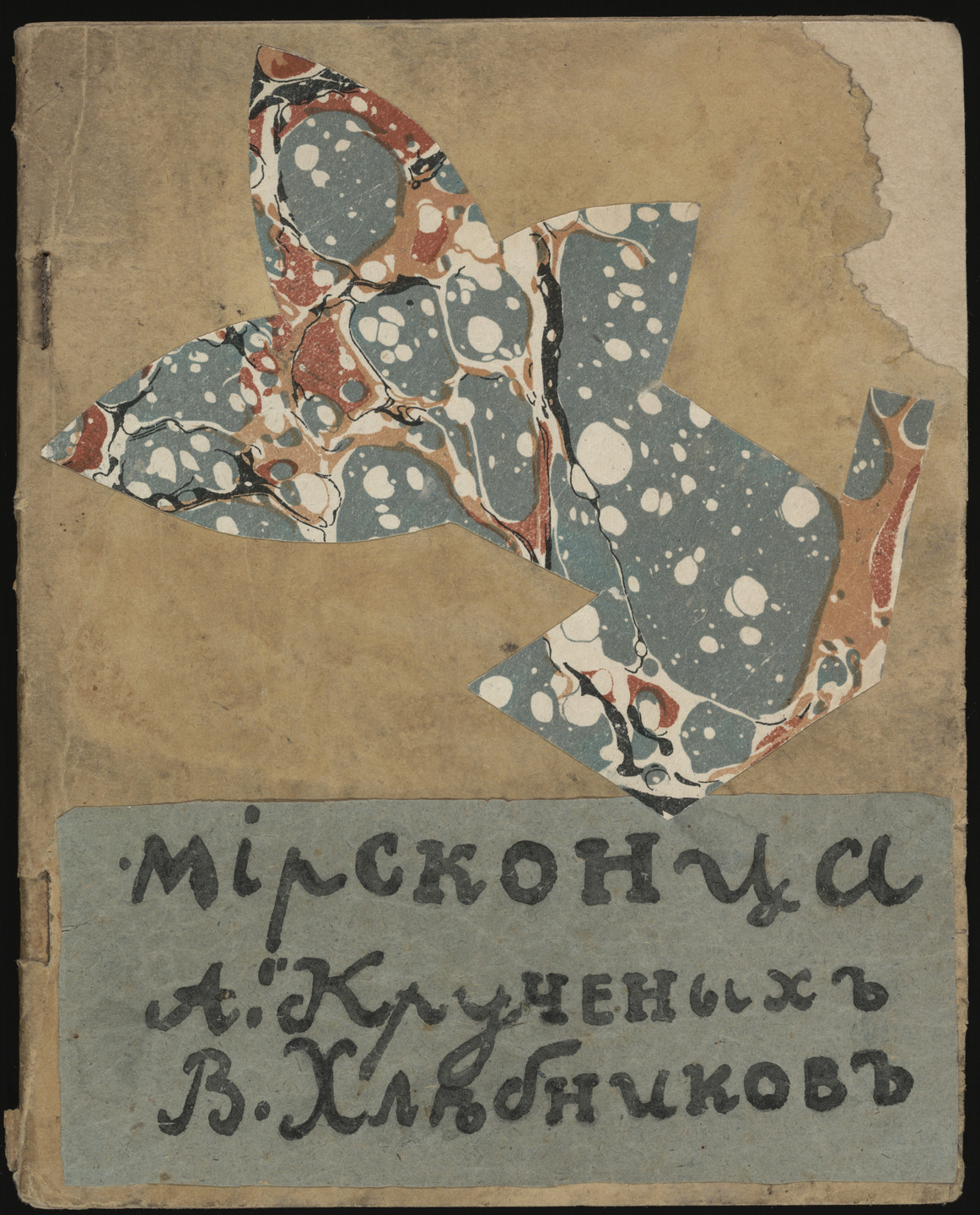 The image shows a worn, tan-colored book cover with a multicolored design resembling a bird made of blue, white, and red marbled paper. Below the design, there is black text on a blue background. This is an AI generated description. To give feedback, email ai@moma.org.