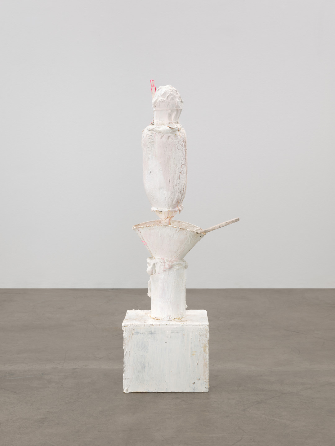 A predominantly white sculpture with rough textures stands on a white square base. It consists of multiple stacked shapes, with small red details at the top. This is an AI generated description. To give feedback, email ai@moma.org.