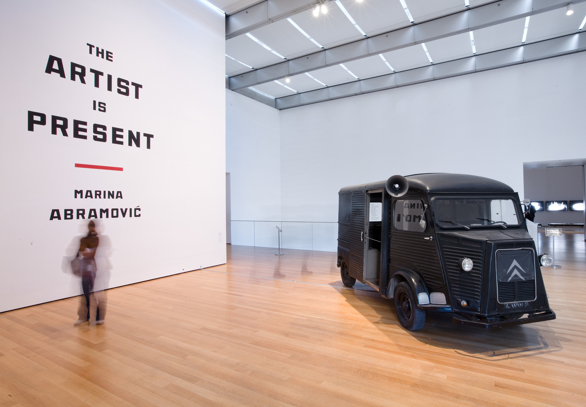 Entrance to the exhibition Marina Abramović: The Artist is Present, The Museum of Modern Art, 2010. Photo by Jason Mandella. In this photo: Marina Abramović and Ulay, Relation in Movement, 1977. Video (black and white, silent), sound environment (2010), Citroën Type H bus, fourteen black-and-white photographs, and megaphone 34:50 min. Musée d’Art Contemporain de Lyon; video and sound environment courtesy the artist and Sean Kelly Gallery. © 2010 Marina Abramović. Courtesy the artist and Sean Kelly Gallery/Artists Rights Society (ARS), New York