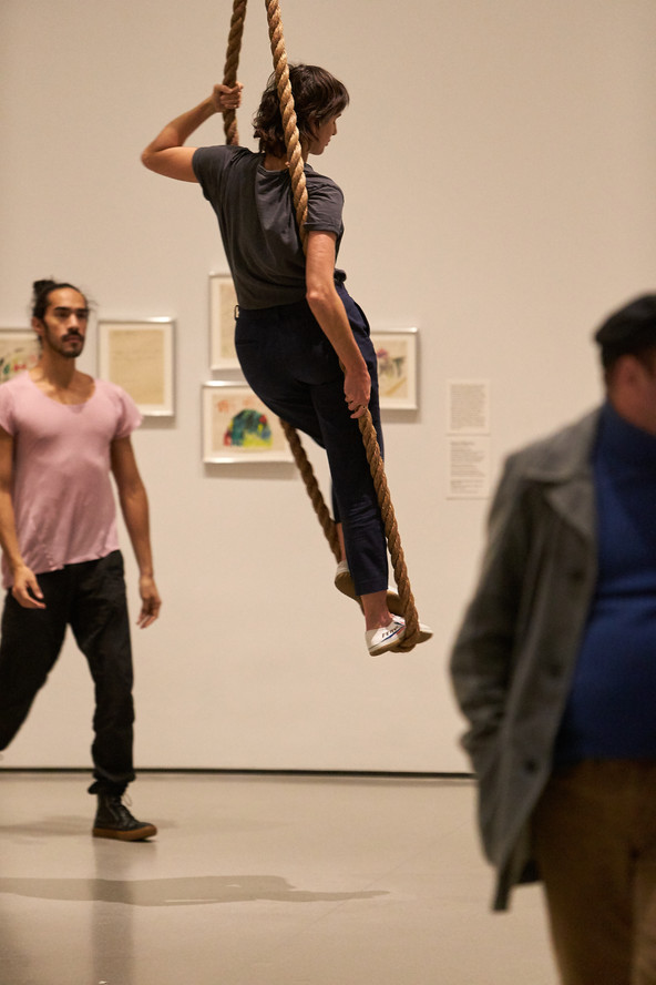 In Accompaniment for La Monte’s “2 sounds” and La Monte’s “2 sounds” (1961), Jessie Gold stands in a rope loop hanging from the ceiling. Miguel Ángel Guzmán winds up and releases the rope. 2 sounds was recorded by La Monte Young on Anna Halprin's Dance Deck, an outdoor performance and workshop space in northern California, the previous year and features two sounds, as stated in the title: the sound of metal scraping on glass, and metal scraping against wood. Rather than having the choreography follow a musical composition, as in traditional dance, Forti inverts this relationship so dance accompanies the music.