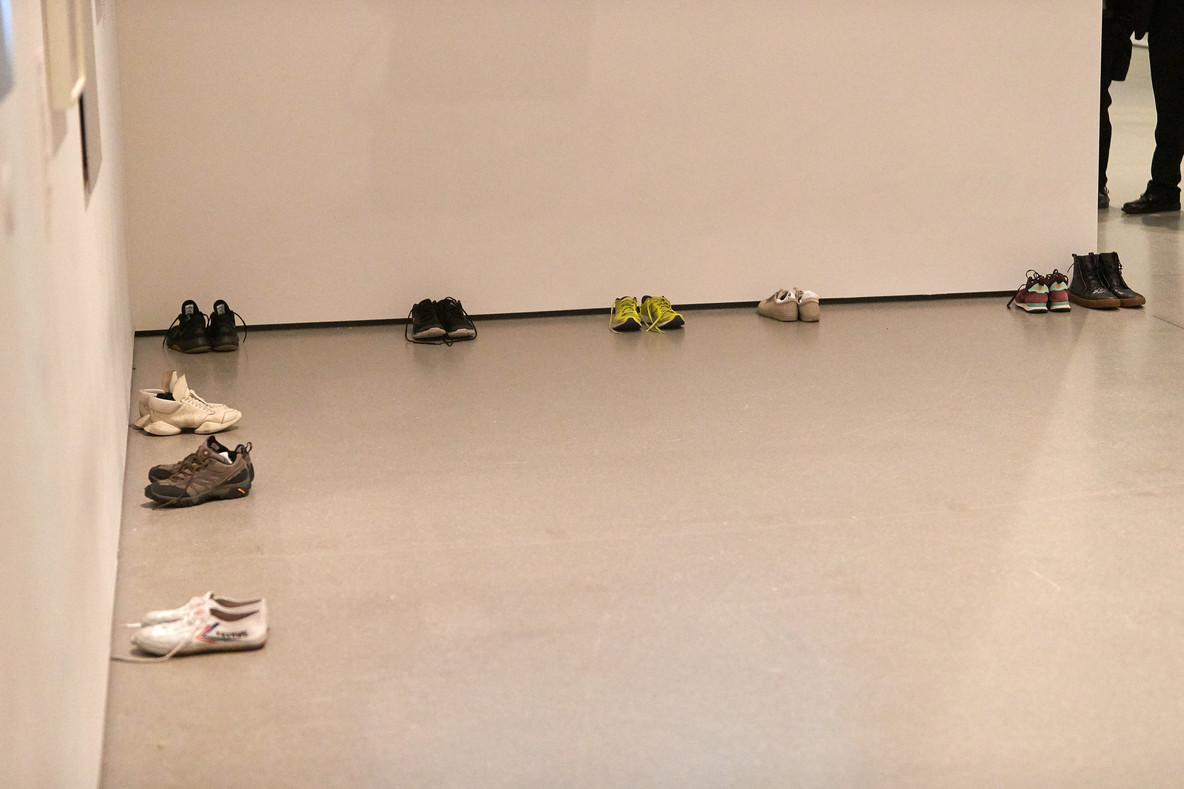 The performers place their shoes in the corner of the gallery and prepare for the first performance, Huddle.