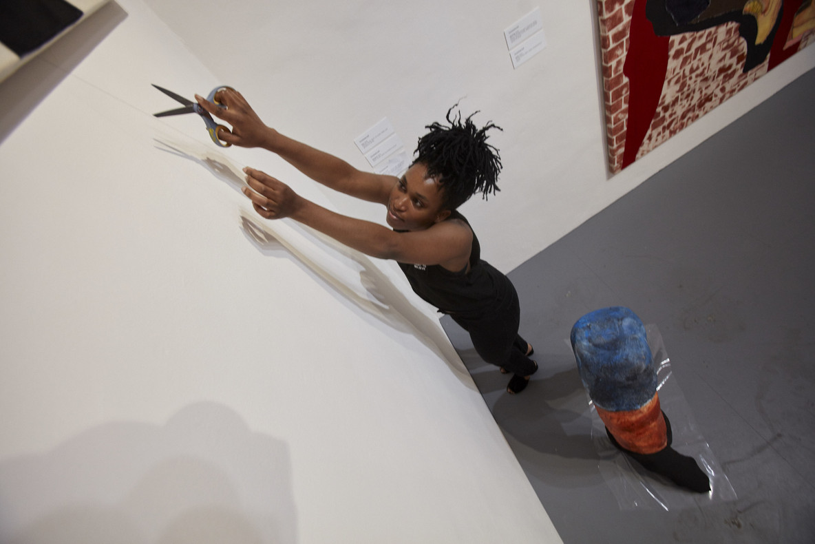 Tschabalala Self cutting a loose thread from a painting