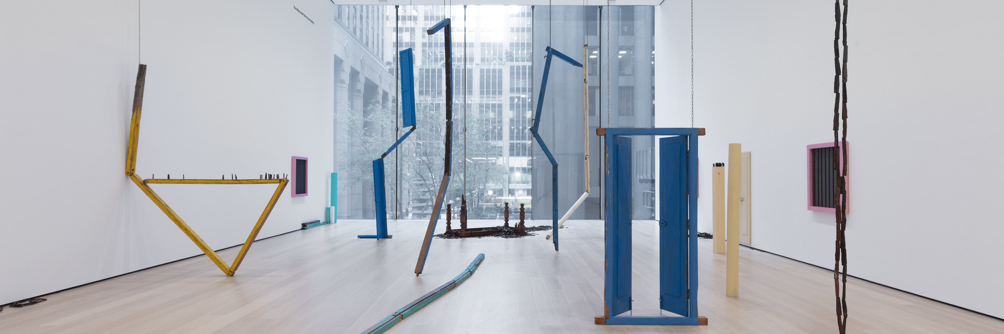 Sheela Gowda. Of All People. 2011. Wood doors, shutters, doorframes, windows, pillars, table and fragments, framed photographs, wood chips, and metal chains, overall dimensions variable. Committee on Painting and Sculpture Funds. © 2019 Sheela Gowda. Installation view, The Museum of Modern Art, New York, 2019. Digital Image © 2019 MoMA, NY. Photo: John Wronn