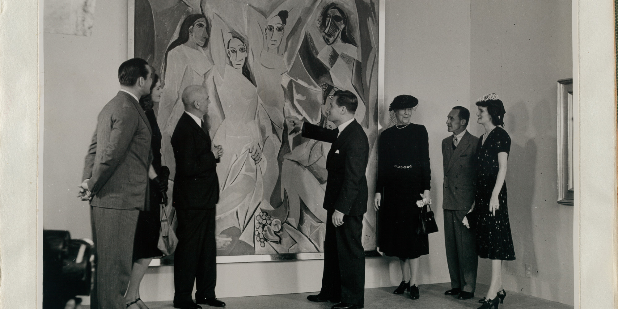 Pablo Picasso’s *Les Demoiselles d’Avignon (1907), upon its acquisition. From left: John Hay Whitney, Lily Emmet Cushing, A. Conger Goodyear, Nelson A. Rockefeller, Jeanie Sheppard, Edsel Ford, and Elizabeth Bliss Parkinson. 1939. A. Conger Goodyear Scrapbooks, 52
