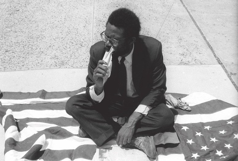 Pope.L, Eating the Wall Street Journal, early street version. 1991. © Pope.L. Courtesy the artist