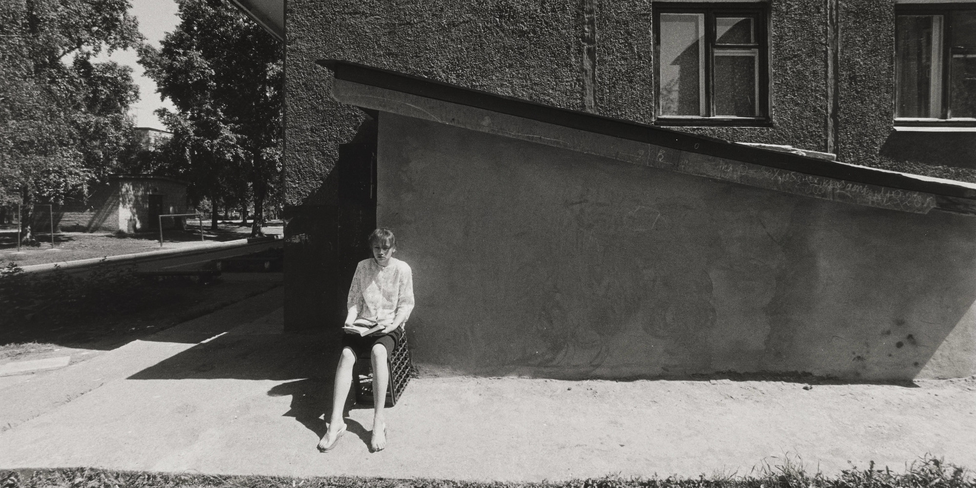Alexander Slussarev. Untitled. (woman reading book, sitting on crate). 1994. Gelatin silver print, 9 13/16 × 14 11/16&#34; (25 × 37.3 cm). E.T. Harmax Foundation Fund