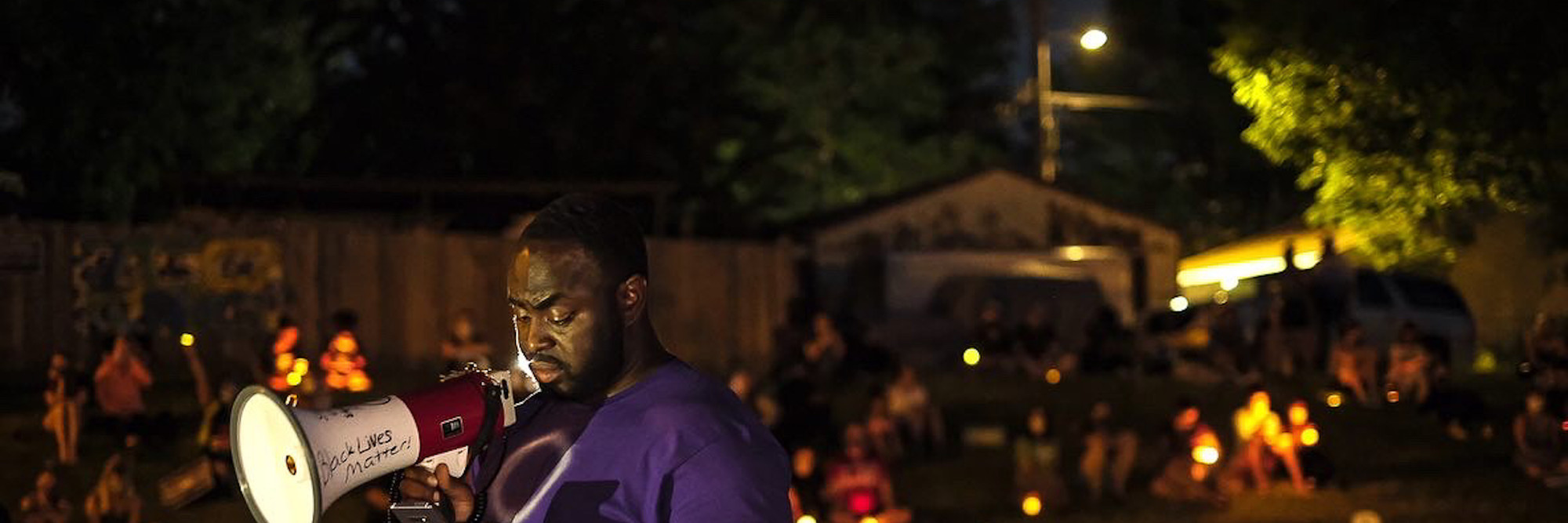 A young man reads out the names of police violence victims—those also present on the makeshift tombstones in the park—aloud to a crowd in Powderhorn, Minneapolis. Picture and caption by Laylah Amatullah Barrayn © 2020
