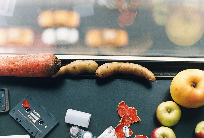 Wolfgang Tillmans. still life, New York . 2001. Image courtesy of the artist, David Zwirner, New York/Hong Kong, Galerie Buchholz, Berlin/Cologne, Maureen Paley, London Image description: A horizontally oriented photograph shows a close-up view of a windowsill. A carrot, fingerling potatoes, apples, vegetable peels, a cassette tape, and an empty film canister are scattered near the windowpane, with a blurry view of a city street below.