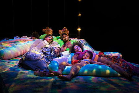 Black Power Naps installation at Performance Space, 2019. Courtesy of Black Power Naps. Photo: Avi Avion Image description: Four adults and one child sleep on colorfully dyed cushions under soft, dappled lighting.