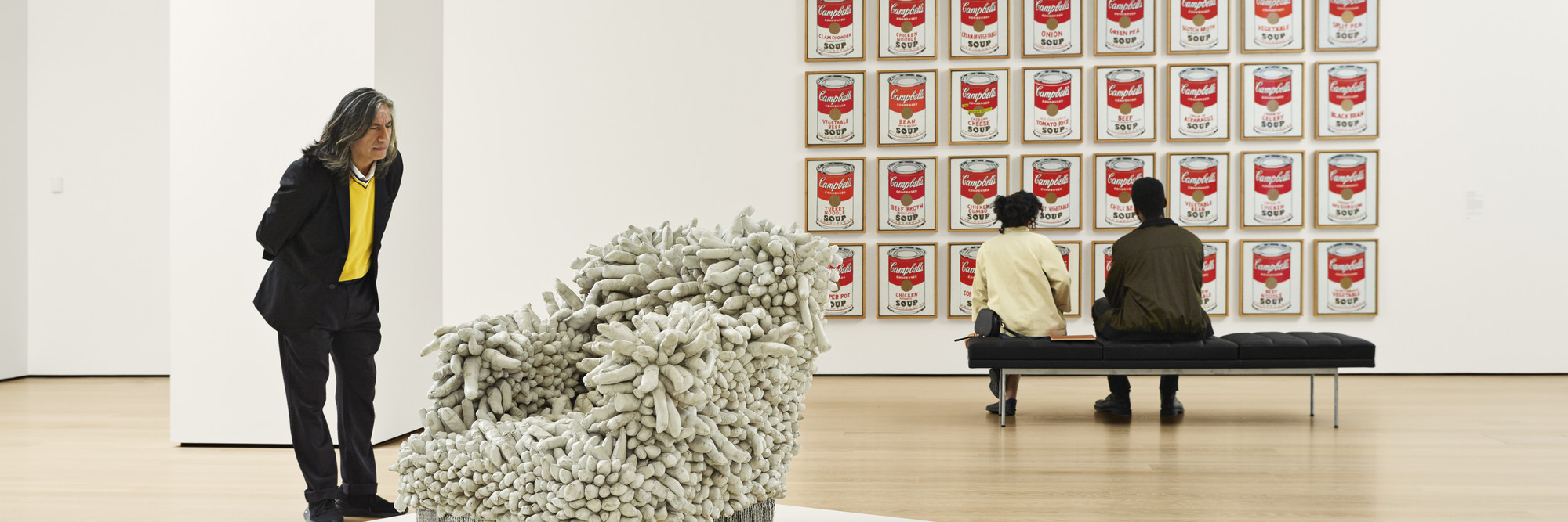 Installation view of the fourth-floor collection galleries. Shown (from left): Yayoi Kusama. Accumulation No. 1. 1962. Sewn stuffed fabric, paint, and chair fringe. The Museum of Modern Art, New York. Gift of William B. Jaffe and Evelyn A. J. Hall (by exchange). © 2023 Yayoi Kusama; Andy Warhol. Campbell’s Soup Cans. 1962. Acrylic with metallic enamel paint on canvas, 32 panels. The Museum of Modern Art, New York. Partial gift of Irving Blum Additional funding provided by Nelson A. Rockefeller Bequest, gift of Mr. and Mrs. William A. M. Burden, Abby Aldrich Rockefeller Fund, gift of Nina and Gordon Bunshaft, acquired through the Lillie P. Bliss Bequest, Philip Johnson Fund, Frances R. Keech Bequest, gift of Mrs. Bliss Parkinson, and Florence B. Wesley Bequest (all by exchange). © 2023 Andy Warhol Foundation/ARS, NY/TM. Licensed by Campbell's Soup Co. All rights reserved. Photo: Noah Kalina