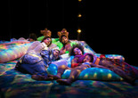 Black Power Naps installation at Performance Space, 2019. Courtesy of Black Power Naps. Photo: Avi Avion Image description: Four adults and one child sleep on colorfully dyed cushions under soft, dappled lighting.