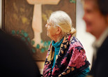 Photo: Jason Brownrigg ©️ 2023 The Museum of Modern Art, New York. Image description: Profile of a smiling woman with white hair and a purple floral scarf turned to look to the left in front of a brown and blue painting that fills the wall behind her.