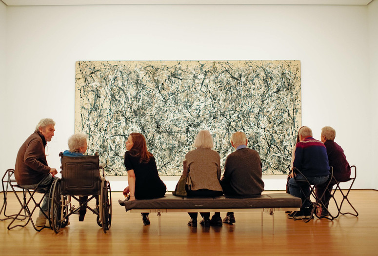 Photo: Jason Brownrigg ©️ 2024 The Museum of Modern Art, NY. Image description: Eight adults seated, facing Jackson Pollock’s One: Number 31, a wall-filling beige canvas scattered with dark gray, white, blue, and tan drips that erratically swing in abstract movement.