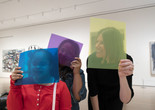 Photo: Martin Seck. © 2023 The Museum of Modern Art, New York Image description: A smiling girl in a red shirt holds a sheer blue square in front of her face alongside two smiling women holding purple and yellow squares.