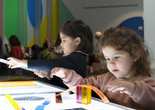 Photo: Martin Seck Image description: Two children build with transparent shapes and lines at a glowing light table