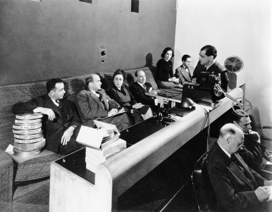 Luiis Buñuel (standing behind film projector) at a meeting in MoMA’s projection room, 1942. From left: Ed Kerns, Kenneth Macgowan, Iris Barry, Gustavo Pittaluga, Mercedes Megwinoff, Eduardo Ugarte, Luis Buñuel, Norbet Lust, and Arthur Kross