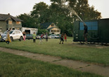 LaToya Ruby Frazier. Shea Cobb, Amber Hasan, and Her Children, Nieces, and Nephews (Zari, DJ, Jayda, Justin, Justace, Jaylen) and Their Friends Playing in the Water Moses West Is Spraying from His Atmospheric Water Generator on North Saginaw Street Between East Marengo Avenue and East Pulaski Avenue on July 29, 2019, Flint, Michigan, from Flint is Family in Three Acts, 2019. © 2024 LaToya Ruby Frazier. Courtesy of the artist and Gladstone Gallery
