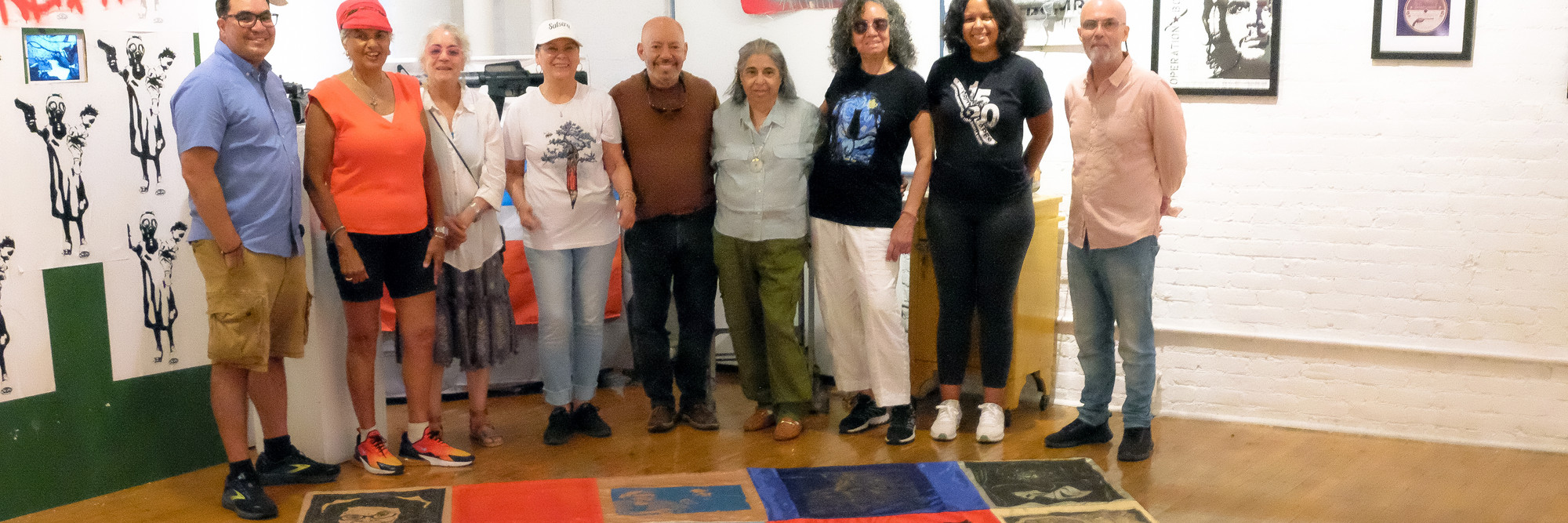 Artists from Rafael Tufiño Printmaking Workshop at Taller Boricua with Campechada 2024 banners dedicated to Victoria Espinoza. From left: Oliver Rios, Betty Cole, Ada Pillar Cruz, Minerva Gonzalez, Eliezer Berrios, Nitza Tufiño, Carmen Ayala, Mariana Ayala, and James Cuebas, 2024. Photo: Oliver Rios