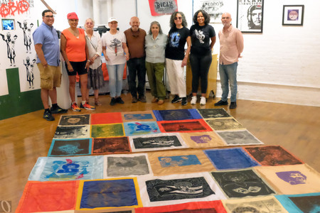 Artists from Rafael Tufiño Printmaking Workshop at Taller Boricua with Campechada 2024 banners dedicated to Victoria Espinoza. From left: Oliver Rios, Betty Cole, Ada Pillar Cruz, Minerva Gonzalez, Eliezer Berrios, Nitza Tufiño, Carmen Ayala, Mariana Ayala, and James Cuebas, 2024. Photo: Oliver Rios