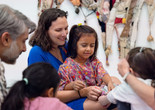 Photo: On White WallImage description: A caregiver sits with a child and smiles