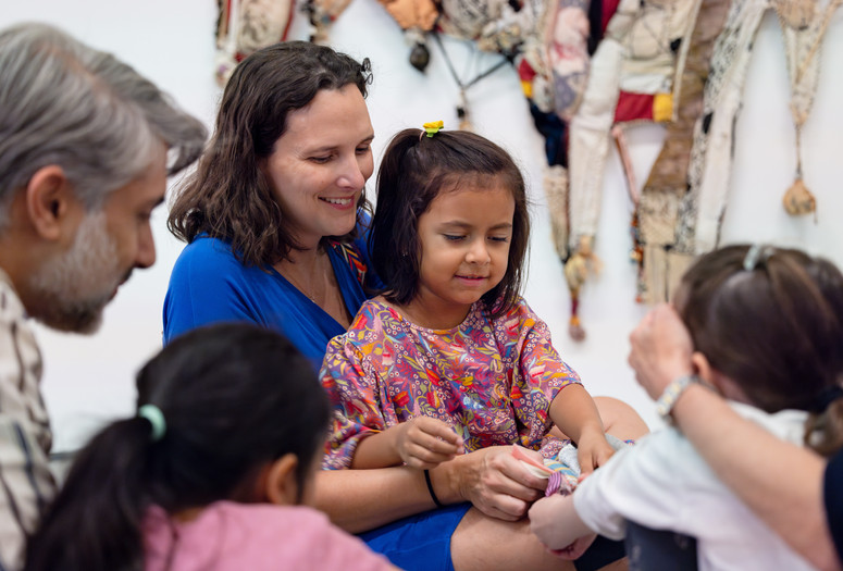 Photo: On White WallImage description: A caregiver sits with a child and smiles