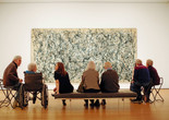 Photo: Jason Brownrigg. Digital image © 2024 The Museum of Modern ArtImage description: Eight adults seated, facing Jackson Pollock’s One: Number 31, a wall-filling beige canvas scattered with dark gray, white, blue, and tan drips that erratically swing in abstract movement.