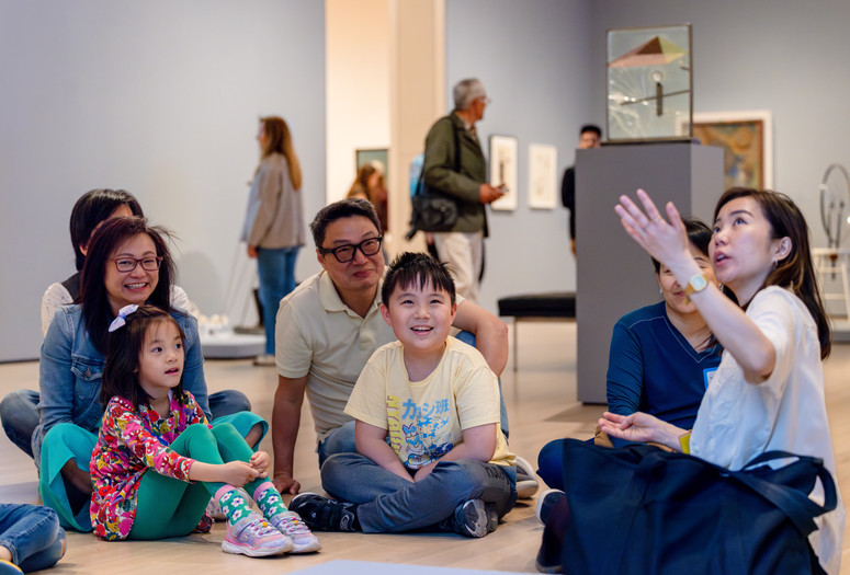 Photo: On White Wall, Inc.Image description: Instructor explains artwork to smiling families.