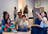 Photo: On White Wall, Inc.Image description: An instructor explains an artwork to smiling families.