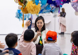 Photo: On White Wall Inc.Image description: An educator engages a group of children in front of a hanging sculpture.