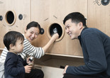Photo: Martin SeckImage description: Parents and young child listing to the sounds materials make at the Listening Wall in Art Lab: Sound.