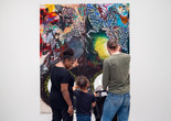 Photo: On White Wall Inc.Image description: A child looks at an artwork on the wall alongside two caregivers.