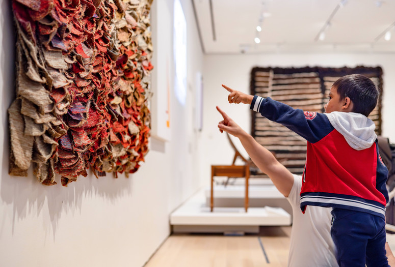Photo: On White Wall Inc.Image description: A child and a caregiver point up at an artwork on the gallery wall.