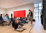 Photo: On White Wall Inc.Image description: An educator points at an artwork and leads a group of families in a discussion.