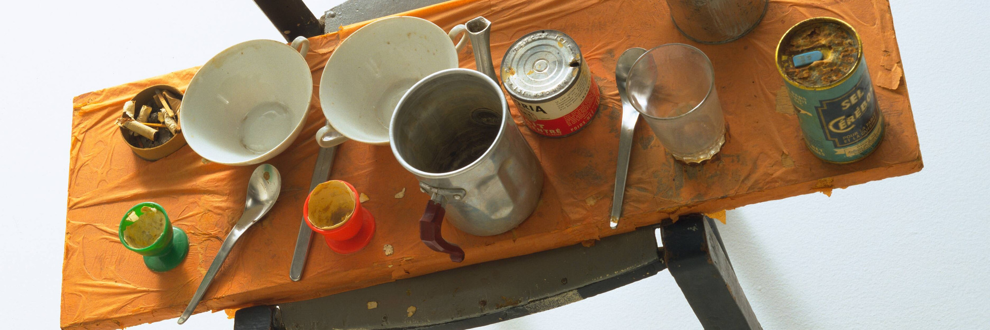 Daniel Spoerri. Kichka&#39;s Breakfast I. 1960. Wood chair hung on wall with board across seat, coffeepot, tumbler, china, eggcups, eggshells, cigarette butts, spoons, tin cans, and other materials, 14 3/8 x 27 3/8 x 25 3/4&#34; (36.6 x 69.5 x 65.4 cm). Philip Johnson Fund. © 2025 Daniel Spoerri / Artists Rights Society (ARS), New York / ProLitteris, Switzerland