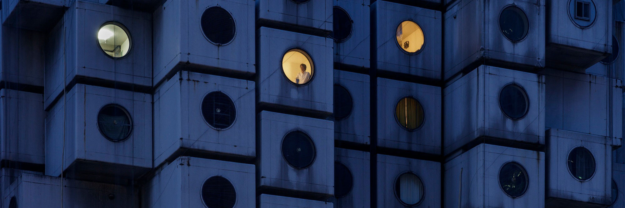 Night time at the Nakagin Capsule Tower, with Mr. Takayuki Sekine seen through the window of capsule B1004, 2016. © Jeremie Souteyrat